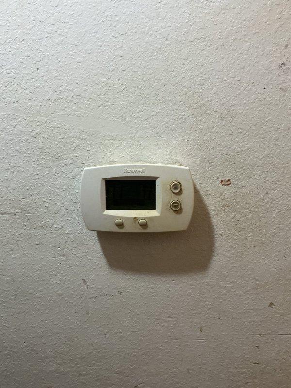 Conducted comprehensive assessment of existing HVAC system for replacement quote. Documented aging exterior condensing unit showing signs of weathering, mounted on concrete pad with associated electrical disconnect box and conduit. Also examined Honeywell digital thermostat which appeared to be non-operational during inspection.