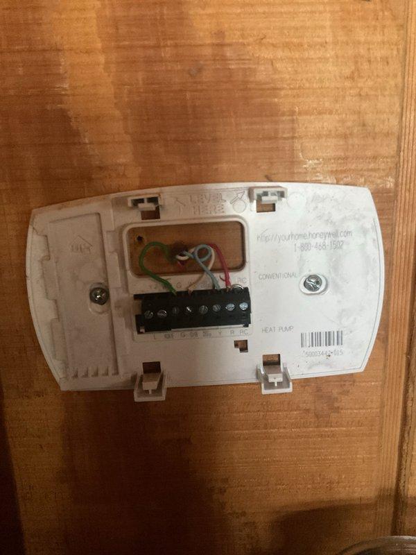 Performed comprehensive HVAC replacement estimate at log cabin residence with existing system showing operational inefficiencies. Inspection revealed weathered outdoor unit with significant algae/mold growth and oxidized copper lines, along with examination of existing Honeywell thermostat wiring configuration to determine compatibility with potential replacement options.