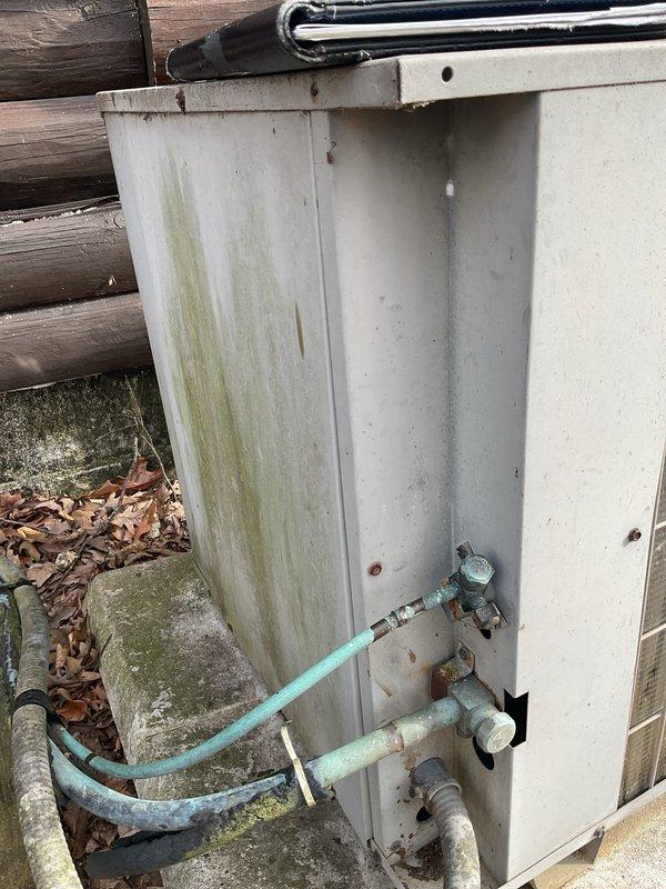 Performed comprehensive HVAC replacement estimate at log cabin residence with existing system showing operational inefficiencies. Inspection revealed weathered outdoor unit with significant algae/mold growth and oxidized copper lines, along with examination of existing Honeywell thermostat wiring configuration to determine compatibility with potential replacement options.