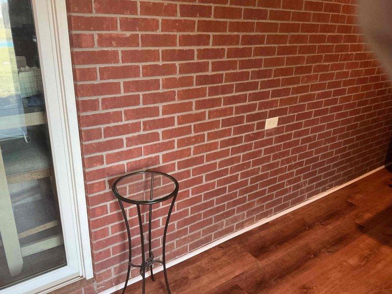 Conducted follow-up assessment of porch addition project. Documented existing electrical outlet on interior brick wall and examined exposed ceiling structure in basement/utility space where electrical connections for the addition will need to be integrated. Photographed both areas to facilitate proper planning for upcoming electrical work.