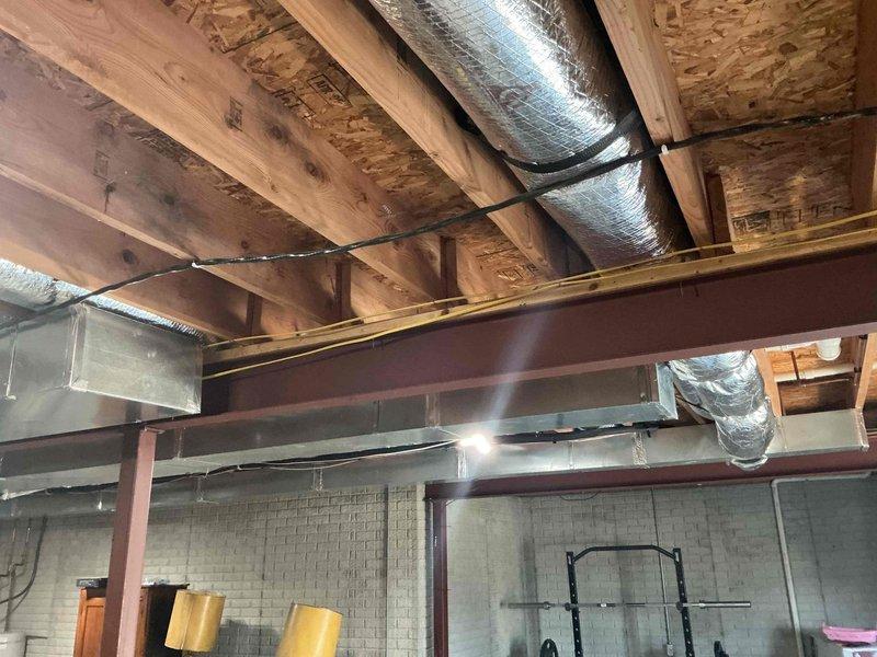 Conducted follow-up assessment of porch addition project. Documented existing electrical outlet on interior brick wall and examined exposed ceiling structure in basement/utility space where electrical connections for the addition will need to be integrated. Photographed both areas to facilitate proper planning for upcoming electrical work.