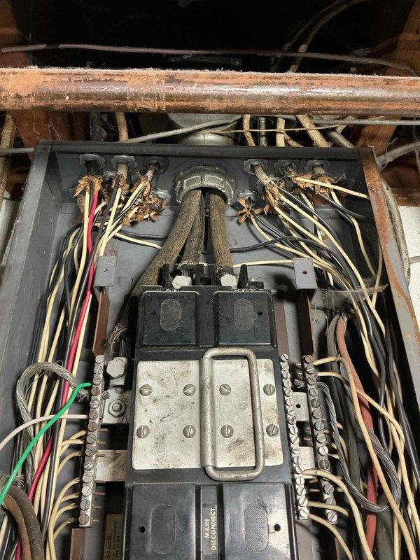 Conducted follow-up inspection of electrical panel as requested by Dave B. Documented significant issues including aged wiring with discoloration, disorganized wire arrangement not meeting current standards, and proximity to severely corroded copper piping. Photos taken revealed deteriorated electrical connections with exposed/fraying wire ends in confined space, indicating urgent need for system upgrade to address safety concerns.