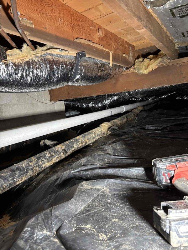 Conducted inspection of crawlspace plumbing infrastructure. Examined multiple PVC drain lines with Y-junction fittings and identified potential issue with copper supply pipe showing discoloration. Assessed HVAC ducting and vapor barrier condition while documenting the current state of plumbing system for future reference.