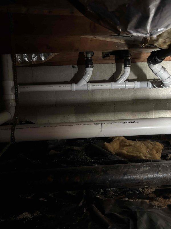 Conducted inspection of crawlspace plumbing infrastructure. Examined multiple PVC drain lines with Y-junction fittings and identified potential issue with copper supply pipe showing discoloration. Assessed HVAC ducting and vapor barrier condition while documenting the current state of plumbing system for future reference.