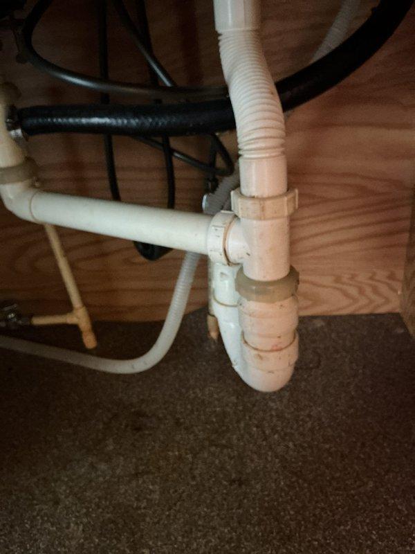 Responded to service call for kitchen drain clog. Inspected under-sink plumbing system including PVC drain assembly with P-trap and flexible corrugated drain pipe. Cleared obstruction and verified proper drainage functionality.