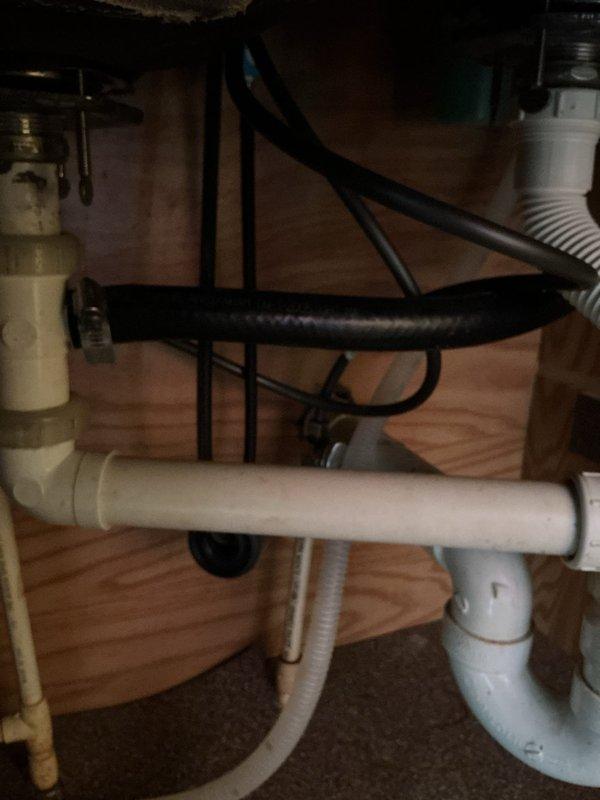 Responded to service call for kitchen drain clog. Inspected under-sink plumbing system including PVC drain assembly with P-trap and flexible corrugated drain pipe. Cleared obstruction and verified proper drainage functionality.