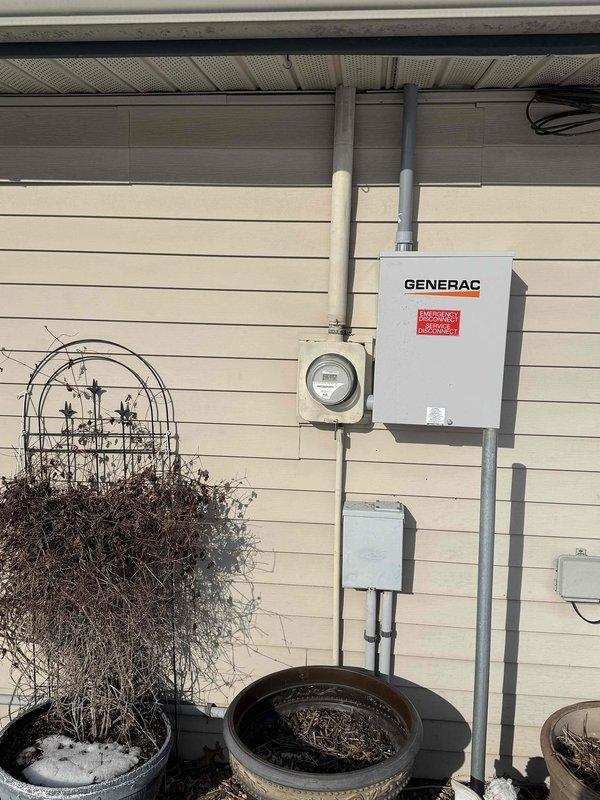 Conducted follow-up site visit to inspect previously installed Generac transfer switch system. Verified proper mounting of transfer switch on exterior wall adjacent to electrical meter enclosure. Took measurements to ensure compliance with installation specifications and documented current condition with photos. No immediate issues requiring correction were identified with the electrical transfer components.