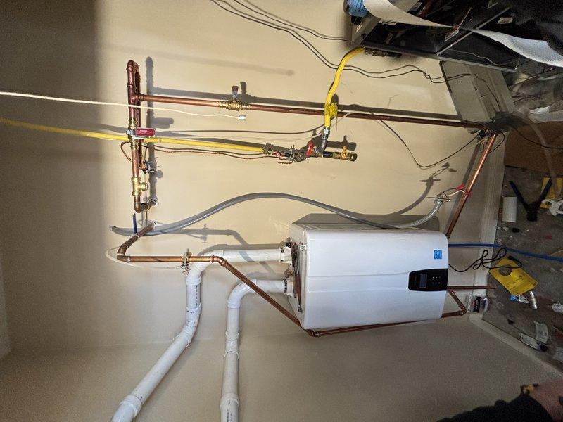 Successfully installed a GREENTankless water heater system with water softener for customer Brad CC. Installation included mounting the tankless unit on the wall, connecting copper supply lines with appropriate valves, installing PVC drain piping, and connecting the yellow gas line. All connections were properly secured and the system was tested for proper operation.