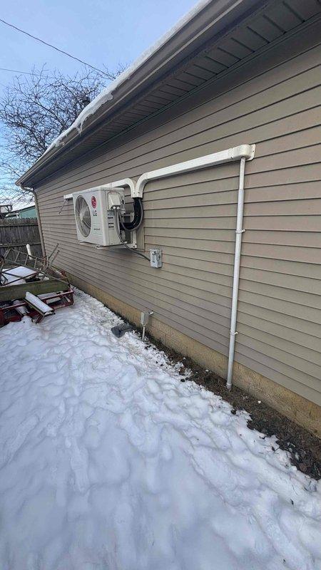 Conducted exterior assessment of existing LG heat pump system during winter conditions. Documented current installation configuration including refrigerant line routing, PVC condensate drainage, and wall penetration. Evaluated equipment for potential replacement, noting current placement considerations and existing line set pathways through vinyl siding exterior.