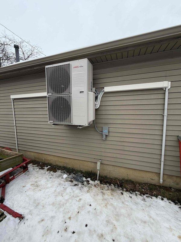 Completed installation of a 20K BTU mini-split system with dehumidification capability on residential property. Mounted outdoor condenser unit on exterior wall with proper elevation above ground level, installed line set with protective PVC covering, and connected electrical components including disconnect box. Indoor air handler was successfully mounted and all connections were completed according to manufacturer specifications.