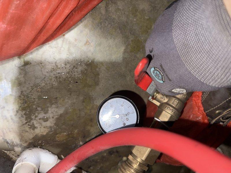 Investigated customer complaint of "battery acid" smell originating from area above heat pump in basement. Conducted pressure testing on system, with gauge readings showing approximately 20 psi. No refrigerant leaks detected that would explain the reported odor.
