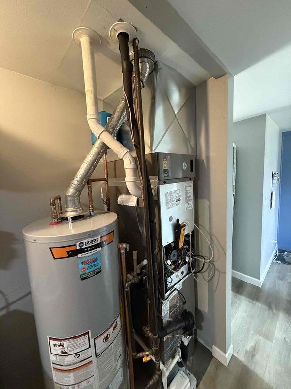 Completed installation of a 40-gallon State gas tall water heater in the utility area. Connected unit to existing copper and PVC plumbing systems, ensuring proper venting and gas line connections. Final inspection confirmed all components properly installed with no leaks or operational issues.
