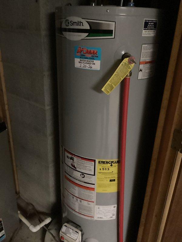 Completed promotional tanked water heater flush service on an A.O. Smith water heater located in utility area. Performed standard maintenance procedure to remove sediment and mineral buildup from tank to improve efficiency and extend equipment life. Documented pre/post service condition with photos showing the unit's installation configuration and proper functioning after maintenance.