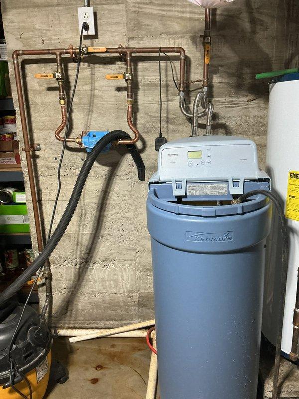 Performed diagnostic inspection of three reported issues: tankless water heater intermittently functioning (likely requiring flushing), non-operational garbage disposal, and malfunctioning Kenmore water softener. Examined water treatment system configuration including copper supply lines, valves, and connections. Visual inspection revealed water softener with open compartment lid and potential issues with internal components.