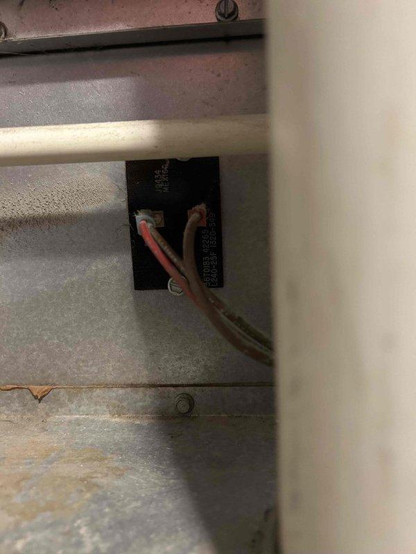 Performed diagnostic service on 20-year-old heating system that was blowing cold air only. Inspected electrical connections at terminal block, focusing on the red and copper wires. Verified proper wire seating and connection integrity at terminal points. System was operational with home temperature at 60°F after service completion.
