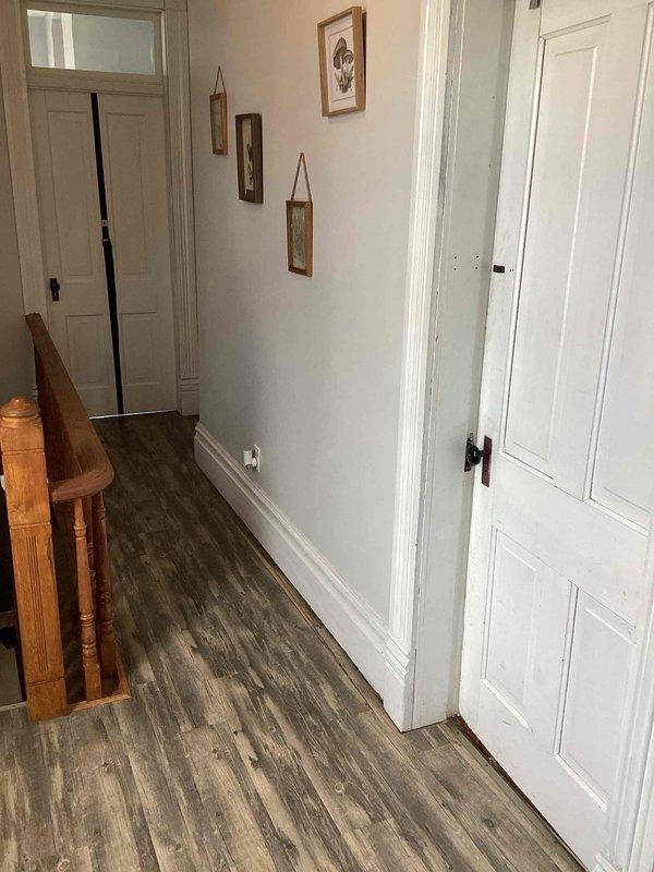 Conducted on-site evaluation of residential property, documenting the interior hallway layout and existing State Proline water heater installation. Noted current water heater setup includes copper supply lines, pressure relief valve, and appears to be installed in basement area with concrete floor and cinder block walls showing signs of deterioration, providing basis for HVAC replacement estimate.