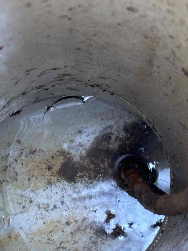 Conducted inspection of sewer system in response to reported cross-contamination between bathroom fixtures and strong sewage odor. Located and accessed outdoor sewer cleanout, revealing significant blockage in main line with standing water. Visual inspection of pipe interior showed deterioration of concrete walls with visible corrosion and sediment buildup, indicating potential need for line cleaning and possible pipe repair.