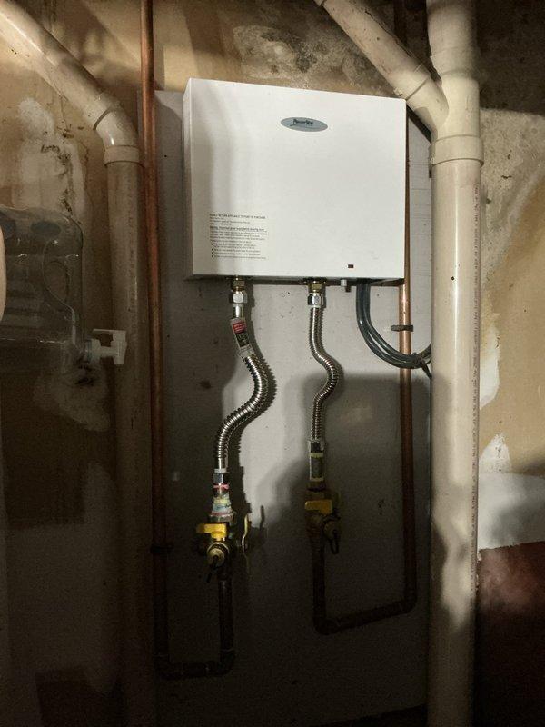 Successfully installed a 50-gallon short propane water heater according to specifications. System includes properly connected stainless steel braided lines with functioning valve handles and appropriate PVC/copper piping integration. Also installed complementary water treatment system featuring a water softener with digital control panel and cylindrical filter housing with all necessary plumbing connections.