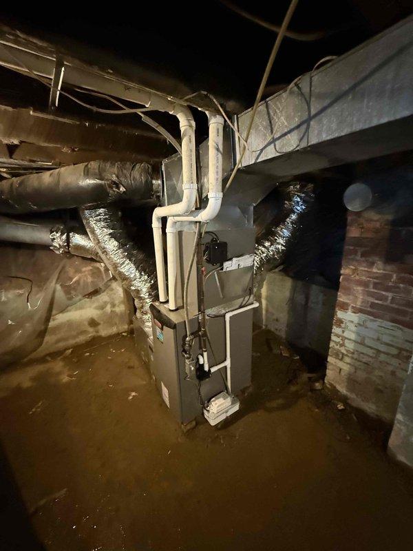 Completed installation of a 2.5-ton, 15.5 SEER 97% efficiency furnace system in basement utility area, including proper venting with PVC pipes and connection to existing ductwork with reflective metallic insulation. Noted moisture concerns in the installation area with visible water staining on concrete surfaces that should be monitored to ensure optimal system performance and longevity.