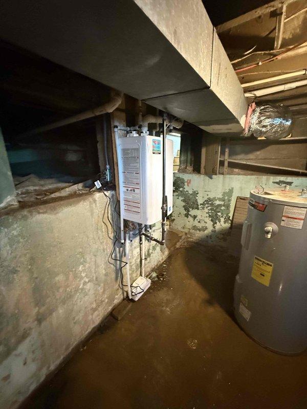 Completed installation of a 2.5-ton, 15.5 SEER 97% efficiency furnace system in basement utility area, including proper venting with PVC pipes and connection to existing ductwork with reflective metallic insulation. Noted moisture concerns in the installation area with visible water staining on concrete surfaces that should be monitored to ensure optimal system performance and longevity.