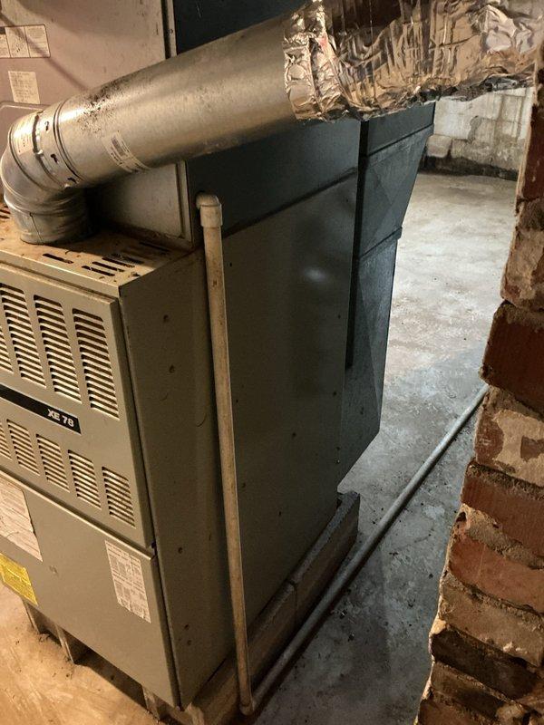 Conducted an assessment of current HVAC system for potential replacement. Existing installation includes an older Trane XL 78 furnace positioned on concrete flooring in utility area with visible ductwork connections secured with metallic tape. System evaluation also included examination of adjacent water heater with pressure relief valve and associated plumbing connections. Photos documented the current equipment configuration and basement mechanical room layout for replacement planning purposes.