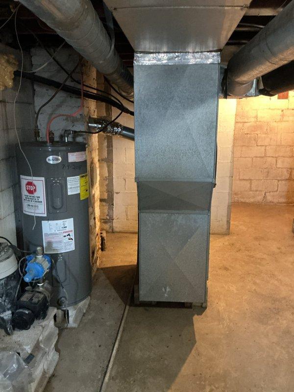 Conducted an assessment of current HVAC system for potential replacement. Existing installation includes an older Trane XL 78 furnace positioned on concrete flooring in utility area with visible ductwork connections secured with metallic tape. System evaluation also included examination of adjacent water heater with pressure relief valve and associated plumbing connections. Photos documented the current equipment configuration and basement mechanical room layout for replacement planning purposes.
