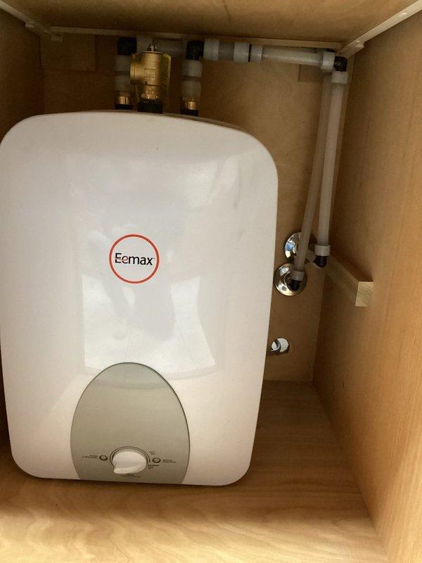 Successfully installed an Eemax tankless water heater unit within a wooden cabinet enclosure. Completed all necessary plumbing connections including PVC piping and brass valves, ensuring proper fitting and secure mounting. System was tested and confirmed to be functioning correctly with temperature controls properly calibrated.