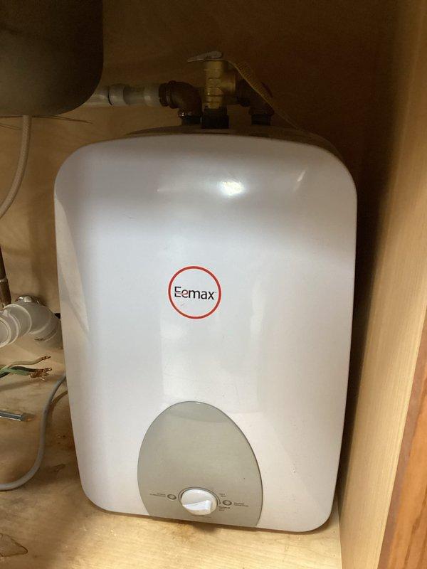 Successfully installed an Eemax tankless water heater unit within a wooden cabinet enclosure. Completed all necessary plumbing connections including PVC piping and brass valves, ensuring proper fitting and secure mounting. System was tested and confirmed to be functioning correctly with temperature controls properly calibrated.