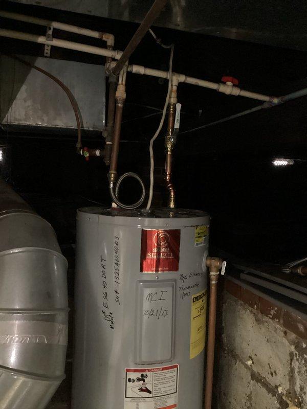 Inspected 120-year-old home's water heater system exhibiting active leakage. Observed significant corrosion and deterioration at the top of the tank with compromised connections to both the PVC vent pipe and copper supply lines. Replaced failed water heater unit, ensuring proper installation of all plumbing connections and verification of system functionality.