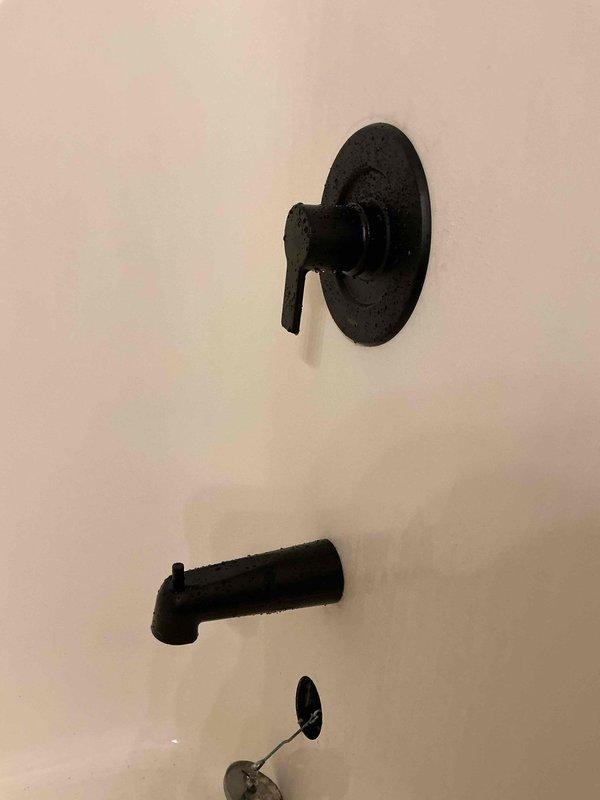 Successfully removed wall behind shower stall to access plumbing, then replaced the existing shower valve assembly with new components. Installed new matte black shower trim kit including valve control with lever handle and matching bathtub spout, completing the fixture upgrade with proper connections to the existing copper supply lines.