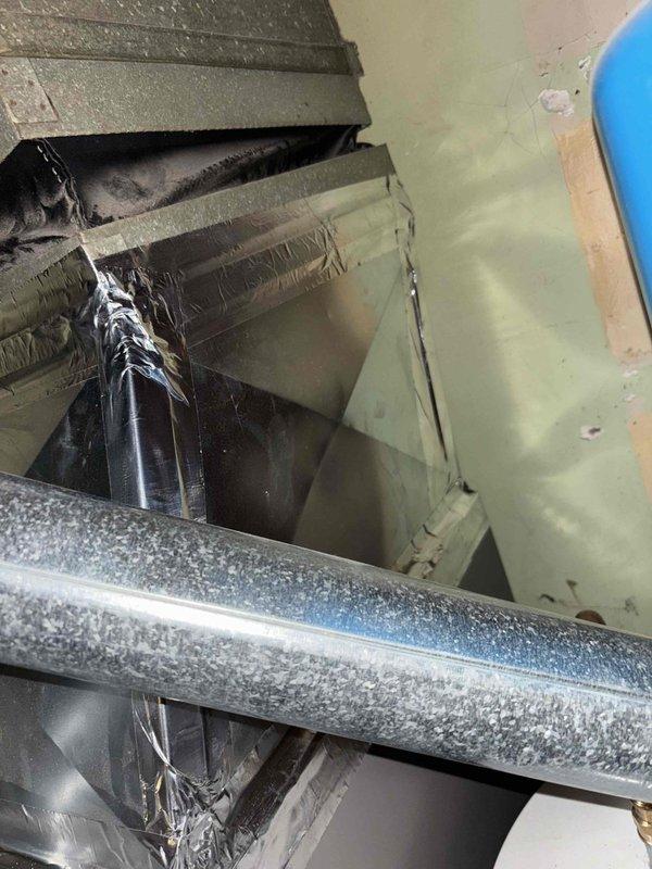 Identified unsealed joints and unsecured bracket in indoor utility closet HVAC system, causing air leakage at multiple connection points. Applied metallic tape to seal exposed seams on galvanized ductwork and properly secured mounting hardware on the main housing panel to restore system integrity and prevent further air loss.