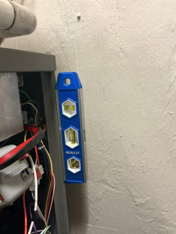Completed annual maintenance on residential HVAC system. Inspected furnace unit, refrigerant lines, and electrical connections using level tool to verify proper equipment alignment. System appears to be in normal working condition with no visible damage or leaks detected.