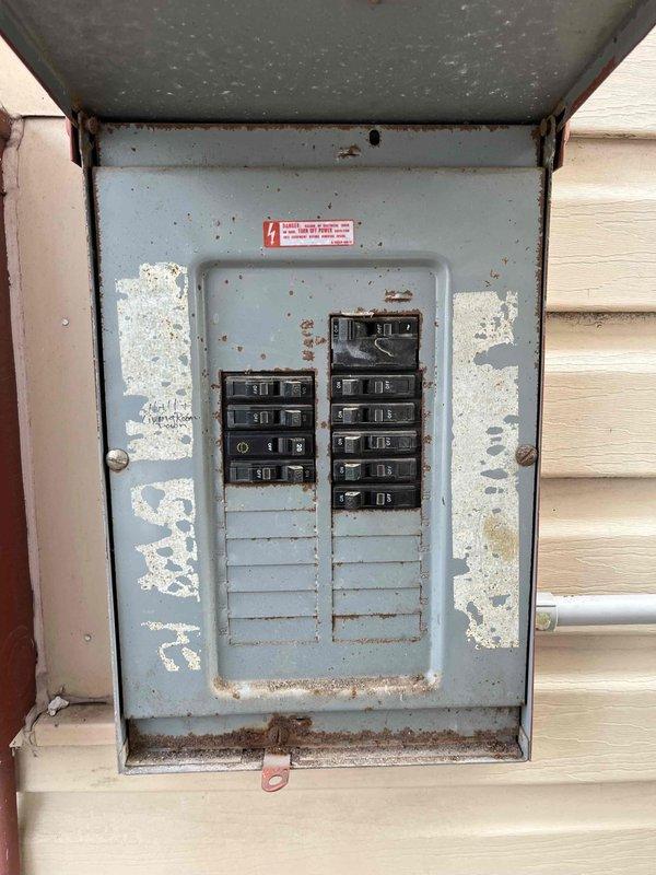 Conducted comprehensive assessment of existing HVAC system for potential replacement. Inspection revealed significant weathering and corrosion on exterior electrical panel with visible rust and deterioration of metal housing. Outdoor AC condenser unit examination showed aging equipment mounted on concrete pad requiring upgrade to improve energy efficiency and system reliability.