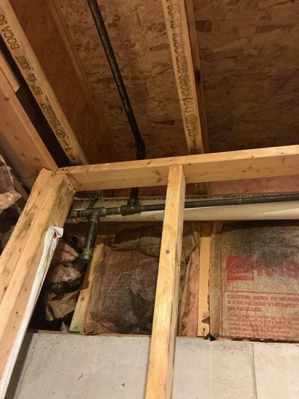 Successfully installed access point for pressure testing of plumbing system by exposing pipe connections through wall framing. Properly navigated around existing insulation and structural elements to ensure complete access to horizontal copper and galvanized steel piping components for accurate diagnostics.