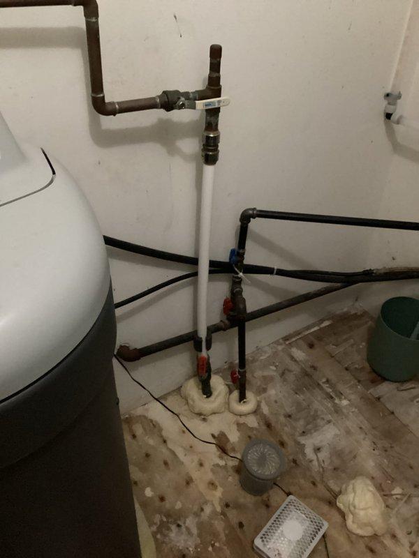 Diagnosed water softener overflow issue causing water puddles near drain. Installed temporary solution to prevent further leaking while providing customer with quote for replacement system. Additionally identified and documented bathroom sink shut-off valve requiring replacement.