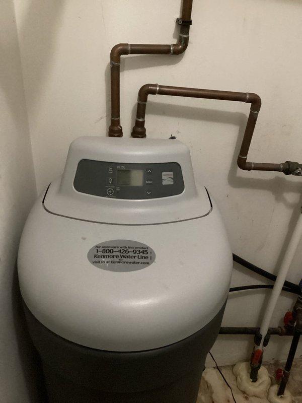 Diagnosed water softener overflow issue causing water puddles near drain. Installed temporary solution to prevent further leaking while providing customer with quote for replacement system. Additionally identified and documented bathroom sink shut-off valve requiring replacement.