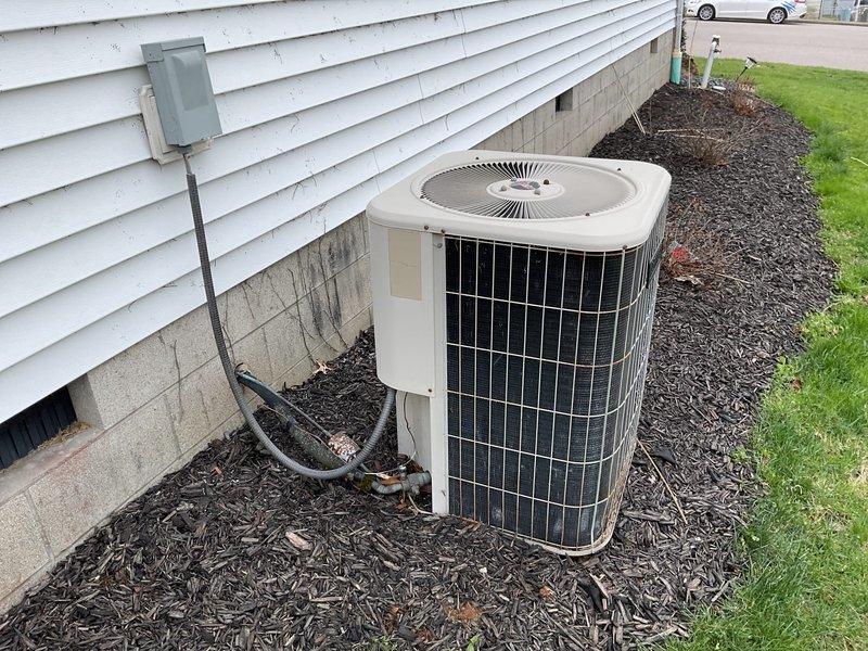 Conducted comprehensive assessment of existing residential HVAC system for potential replacement. Current outdoor condenser unit shows signs of weathering but remains operational, positioned on mulch bedding adjacent to the home's concrete block foundation with proper electrical connections via disconnect box. Customer specifically interested in replacement options only, not repair alternatives.