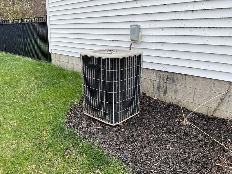 Conducted comprehensive assessment of existing residential HVAC system for potential replacement. Current outdoor condenser unit shows signs of weathering but remains operational, positioned on mulch bedding adjacent to the home's concrete block foundation with proper electrical connections via disconnect box. Customer specifically interested in replacement options only, not repair alternatives.