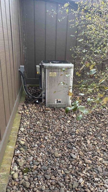 Conducted a comprehensive evaluation of a 40-year-old HVAC system that has ceased functioning. Inspection revealed a severely weathered outdoor condenser unit showing significant dirt accumulation and deterioration, positioned on decorative landscape rocks adjacent to the residence's exterior. Further assessment of the crawlspace identified an aging furnace installation with insulated ductwork requiring replacement. Documented existing system conditions with photographs to support replacement recommendations.