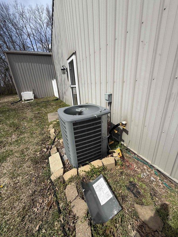 # HVAC System Replacement Estimate Summary

Responded to on-site service call to evaluate existing HVAC system for replacement. Conducted comprehensive assessment of outdoor condensing unit and indoor air distribution components. Exterior inspection revealed aging air conditioning condenser positioned on concrete pad adjacent to building structure, with existing refrigerant line set, electrical disconnect, and junction box requiring evaluation for replacement compatibility. Indoor assessment documented return air grille placement and existing ductwork configuration within conditioned space. Photographed current equipment installation, refrigerant piping routing, electrical connections, and indoor air handler access points to develop accurate replacement specifications. Provided Red-level priority estimate for complete system replacement with A+ equipment tier recommendations based on current system age, condition, and customer requirements for improved efficiency and reliability.