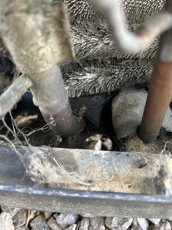 # Service Report

Responded to no-cooling complaint on 15-year-old residential HVAC system. Customer reported outdoor condensing unit not operating while indoor blower ran continuously, producing room temperature air with thermostat set to 68°F showing 75°F indoor temperature.

Upon arrival, confirmed outdoor unit failed to energize when thermostat called for cooling. Verified no tripped breakers at electrical panel. Inspected indoor air handler and found evaporator coil heavily contaminated with dust and debris accumulation, significantly restricting airflow. Drip pan showed extensive dirt buildup and deterioration. System components displayed poor maintenance history with substantial neglect evident throughout.

Performed diagnostic testing on outdoor condensing unit electrical components. Identified failed contactor preventing compressor and condenser fan motor operation. Tested capacitor values and found dual run capacitor reading out of specification, indicating capacitor failure 