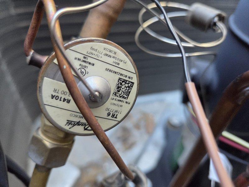 # HVAC Service Report

Responded to no-cooling complaint on 2-year-old AC system with ongoing temperature control issues since installation. Upon inspection, discovered catastrophic refrigerant leak caused by punctured copper suction line. Hole in copper tubing resulted in complete loss of refrigerant charge, preventing system from achieving desired cooling capacity below 79 degrees. Documented damage with photographs showing compromised copper pipe and thermal expansion valve assembly. Leak represents manufacturing defect or installation damage that has progressively worsened over the two-year service period, explaining the chronic underperformance and previous unsuccessful repair attempts.