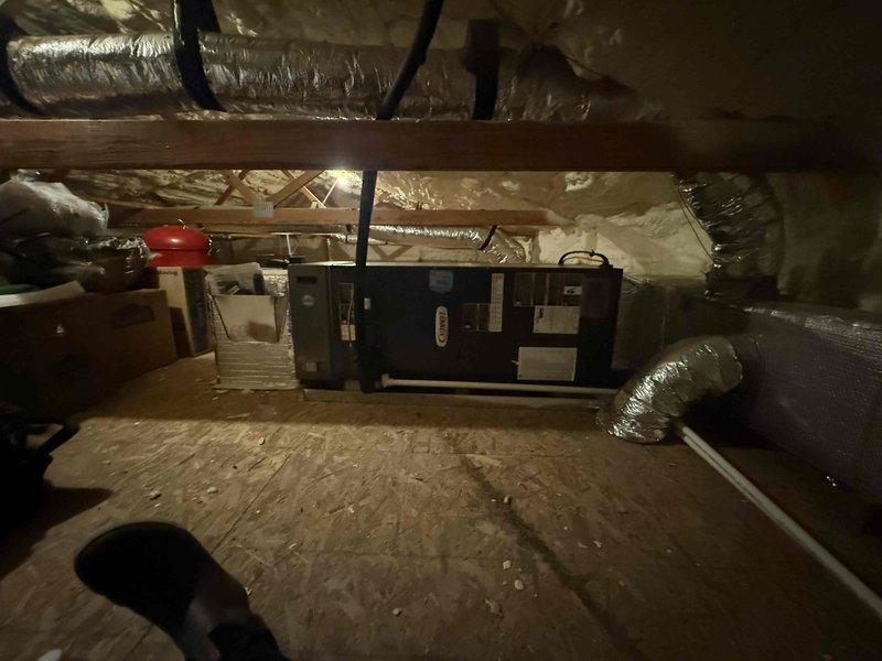 Completed installation of 3-ton, 19 SEER heat pump system including outdoor condensing unit and indoor air handler. Mounted air handler horizontally in attic space with proper clearances, installed new flexible ductwork throughout attic with secure fastening and connections, and positioned outdoor unit on ground-level pad against exterior metal building wall. Ran refrigerant lines, condensate drain piping, and electrical connections between indoor and outdoor equipment, ensuring all components were properly secured and operational per manufacturer specifications.