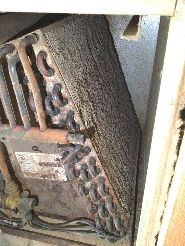 Responded to no-cool call on approximately 20-year-old system in mobile home. Customer reported unit would cool for approximately one hour before freezing up. Upon arrival, system was off and thawing as instructed. Performed diagnostic inspection and found evaporator coil heavily contaminated with thick dust and debris accumulation, severely restricting airflow. Reduced airflow caused coil temperature to drop below freezing point, resulting in ice formation and system shutdown. Explained that extensive contamination was root cause of freezing condition and that coil required professional cleaning or replacement to restore proper operation. Documented coil condition with photographs showing dense black buildup obscuring copper surfaces. Provided recommendations for system restoration and discussed options with property owner.