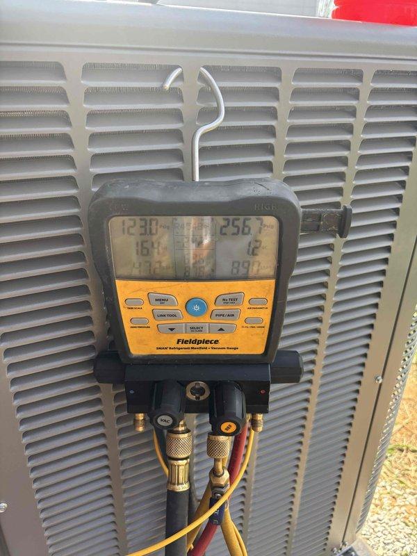 # HVAC Install - Complete System

Successfully completed full system installation including outdoor condensing unit and associated components. Performed comprehensive system commissioning and diagnostics using professional-grade instrumentation. Utilized digital manifold gauge to verify refrigerant pressures and system operating parameters, confirming proper charge levels with readings of 123.0 PSI and 256 PSI on respective service ports. Connected yellow, red, and blue refrigerant hoses to outdoor unit for accurate pressure testing and system evaluation.

Conducted temperature verification at supply ductwork, recording 55.4°F discharge air temperature to confirm proper cooling performance and system efficiency. All measurements taken with calibrated digital instruments to ensure accuracy and compliance with manufacturer specifications. System operating within normal parameters for optimal performance and energy efficiency.