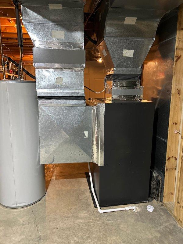 Completed follow-up visit to finalize HVAC installation in residential basement mechanical room. Verified proper installation and connection of Amana furnace unit with associated flexible ductwork system extending to ceiling and wall distribution points. Confirmed galvanized sheet metal ductwork network properly secured and connected to air handler unit with appropriate sealing at all joints and transitions. Documented completed installation showing furnace, air handler, water heater, and full ductwork system operational and ready for service.