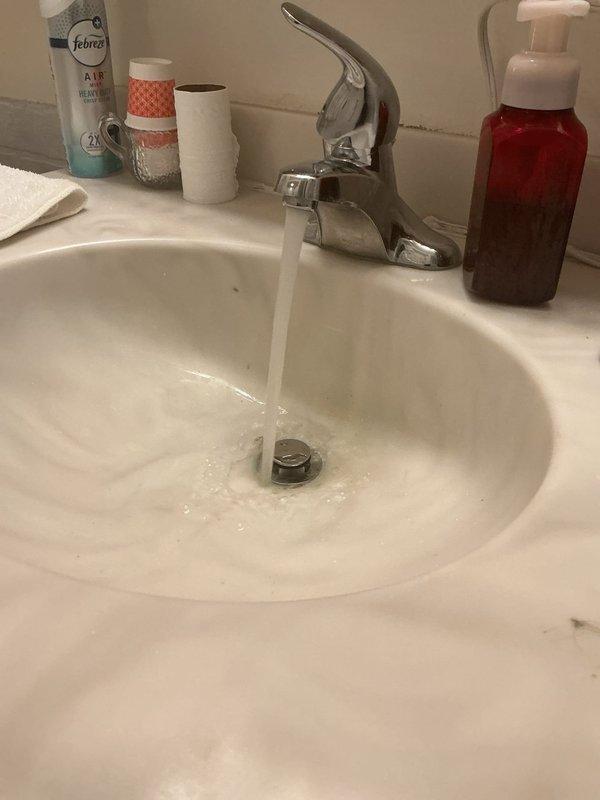 Responded to callback for leak under bathroom sink following recent service visit. Upon inspection, discovered failed corroded pipe fitting causing water seepage beneath vanity. Removed deteriorated metal valve component showing significant oxidation and verdigris buildup. Replaced defective fitting with new assembly, installed fresh washer, and tested faucet operation under full water flow. Verified no leaks present at connections and confirmed proper drainage. Issue resolved and system returned to normal operation.