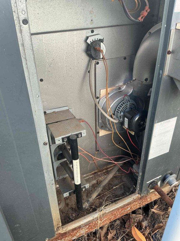 Responded to no heat call with system completely non-operational and no airflow present. Upon inspection, discovered significant environmental debris accumulation including leaves and organic matter in bottom of cabinet, along with corroded copper piping and deteriorated components. Blower motor assembly showed heavy dust buildup and compromised electrical connections with multiple wire terminals affected by contamination. Cleaned debris from cabinet base, restored proper blower motor operation, secured all electrical connections, and verified system functionality with normal airflow restored.