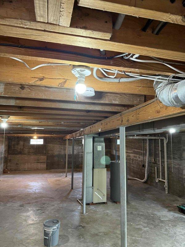Performed comprehensive electrical inspection of residential property including basement and main living areas. Verified proper installation and functionality of smoke detector mounted to ceiling joists in unfinished basement area. Inspected electrical wiring routed along exposed joists, confirming secure cable management and compliance with code requirements. Checked HVAC system electrical connections and verified proper grounding of mechanical equipment. Examined structural support posts and ensured no electrical hazards were present near metal columns.

Inspected main floor electrical components including wall-mounted switches, doorbell system, and low-voltage devices. Verified proper operation of dual-switch light switch plate and confirmed secure mounting of all wall-mounted electrical fixtures. All systems tested and found to be functioning properly with no safety concerns identified.
