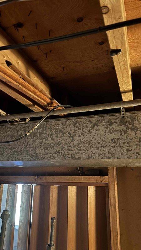 Conducted comprehensive assessment of existing basement cooling system for residential property sized between 1001-1599 square feet to provide replacement estimate. Evaluated current unit configuration, ductwork infrastructure, and installation accessibility in confined crawl space area with exposed structural elements. Documented existing HVAC system conditions including flexible duct routing, electrical connections, and clearance requirements for equipment replacement. Photographed installation site showing spray foam insulation, metal piping runs, and available workspace for new equipment installation to ensure proper sizing and configuration recommendations for replacement cooling system.